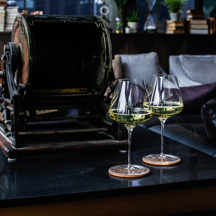 two grassl wine glasses on table filled with white wine