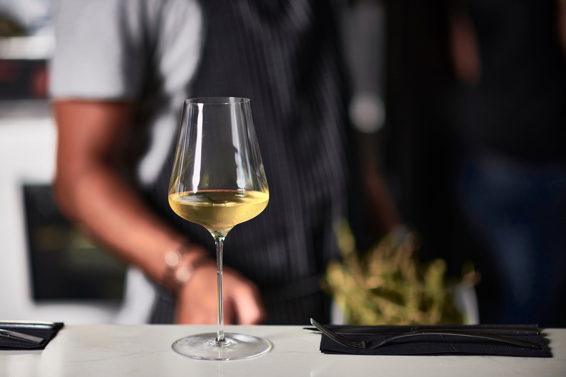 grassl wine glass with white wine on a table in front of a man