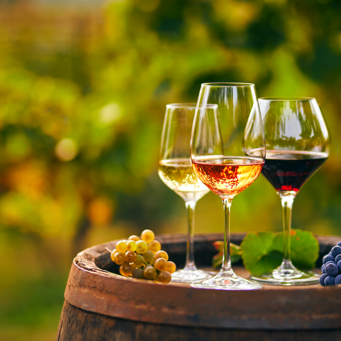 three grassl wine glasses in a vineyard