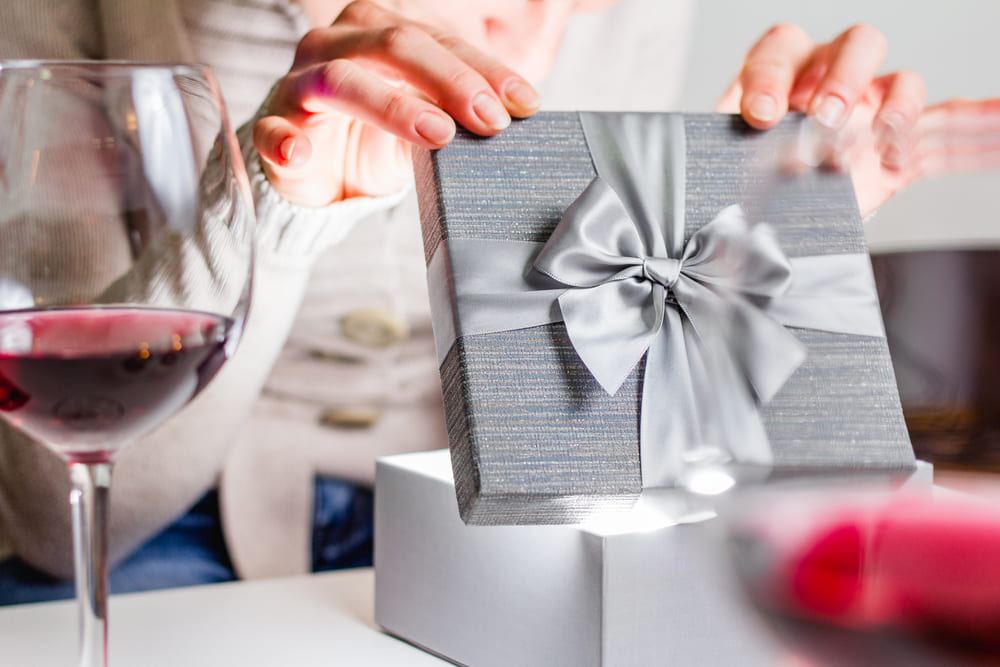 Woman opening a gift with wine glass