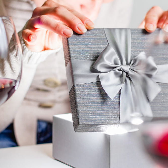 Woman opening a gift with wine glass